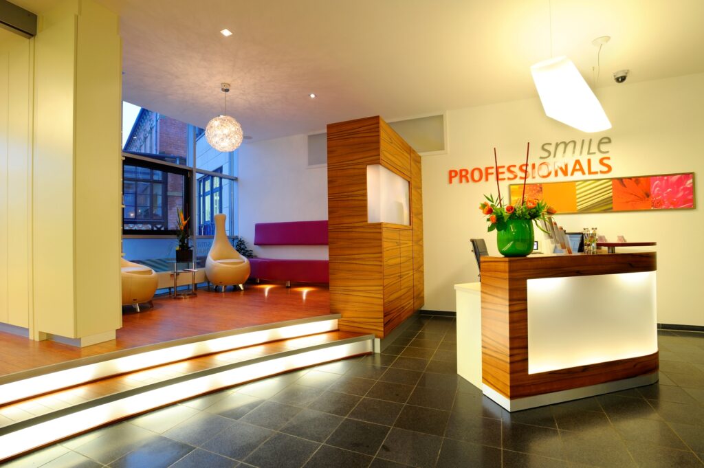 Professionelle Rezeption und Wartebereich eines Prophylaxe-Zentrums wiederspiegelt eine angenehme Atmosphäre gepaart mit zahnmedizischem Können.